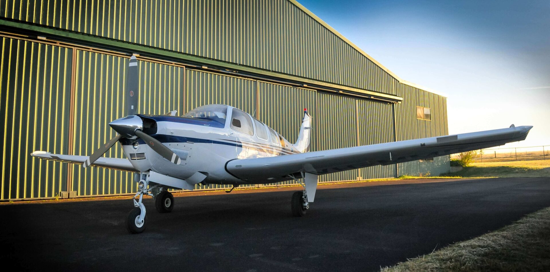 A small airplane parked in front of a hangar.